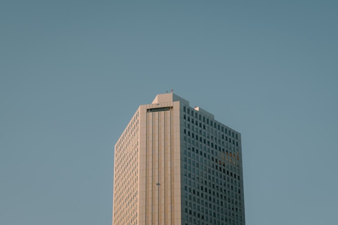 A tall modern office building against a clear blue sky